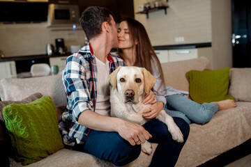 Young couple and their fluffy baby labrador retriever at home in the kitchen