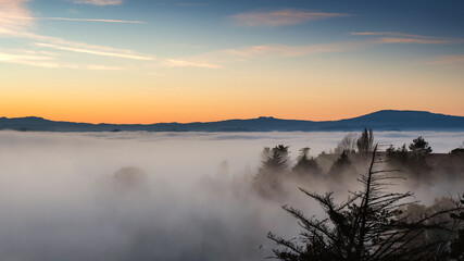 hilly mountain landscape with fog at dawn