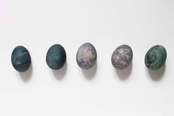 isolated idea shot on white background of a row of five Easter eggs painted with natural paint...