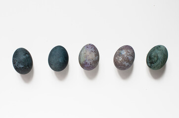 isolated idea shot on white background of a row of five Easter eggs painted with natural paint looking like cosmic planets and galaxies in space