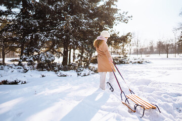 Young woman rolls on a sled in the winter snowy forest. Nature, holidays, rest, travel concept.