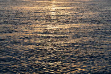 the water surface is golden in the rays of the rising sun. Glare on the water. Light ripples and...
