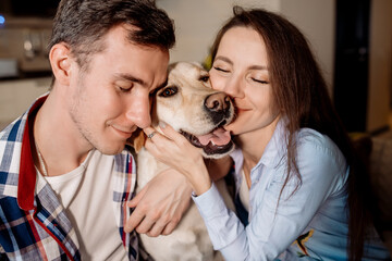 Young couple and their fluffy baby labrador retriever at home in the kitchen