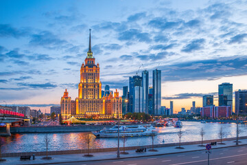 Illuminated high-rise stalinist building near river at evening in Moscow, Russia. Historic name is Hotel Ukraine.