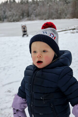 Fototapeta na wymiar happy small child infant playing in snowy winter day