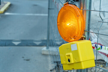 Close-up of a luminous beacon, attached to the fence of a construction site. 