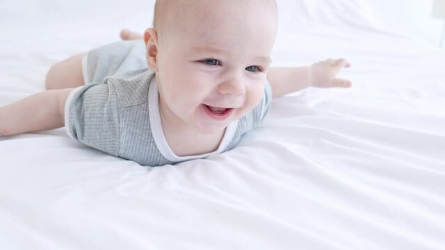 Funny adorable kid infant boy playing pure silky blanket in room