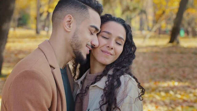 Dreamy arabic couple looking into distance outdoors partners in love enjoy spending time together attractive guy tight hug beautiful curly woman in autumn park amorous close relationship smiling pair