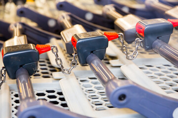 Rows of locked metal shopping carts in supermarket. Close up view.