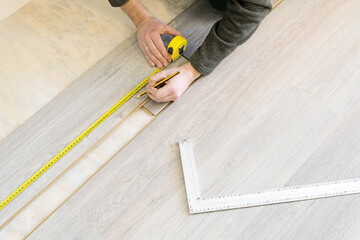 Fototapeta na wymiar DIY, repair, building and home concept - close up of male hands lying parquet floor board/laminate flooring