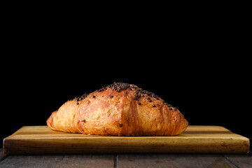 Croissant with chockolate on wooden serving board