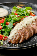 Closeup view of juicy beefsteak with parmesan and fresh vegetables