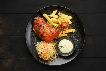 Overhead view of baked chicken leg with american fries and pickled cabbage