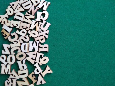 wooden letters of the alphabet scattered on a green background with space for text. High quality photo