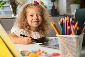 a little girl studies at home, returns to school, the child draws on a graphic tablet