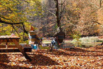Back view of couple sitting on camping chair watching lake in autumn season in sevenlakes (yedigoller), Bolu, Turkey