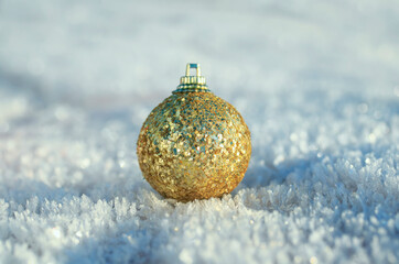 festive toy golden christmas ball lies on snow crystals in the new year's park