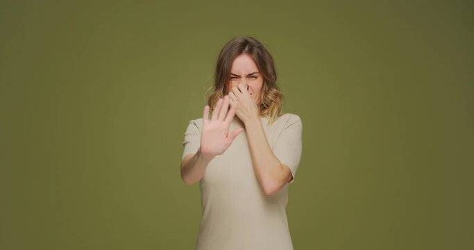 Bad smell and stop gesture. Woman pinching her nose with fingers feel disgusting odor, stink, having aversion