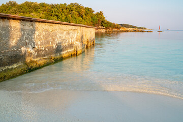 Clear sea water from the turquoise sea washes on the white sandy beach