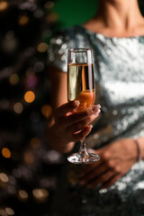Woman holding glass with champagne on a Christmas tree background