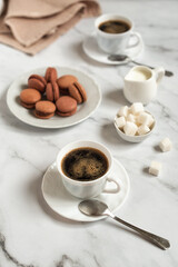 A cup of coffee and macaroons on a light marble background