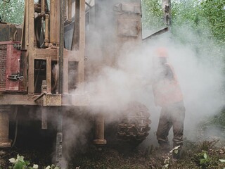 Fototapeta na wymiar Crawler drilling rig drills well, lot of dust when drilling borehole