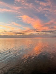 Fototapeta na wymiar colorful sunset clouds over calm bay water 