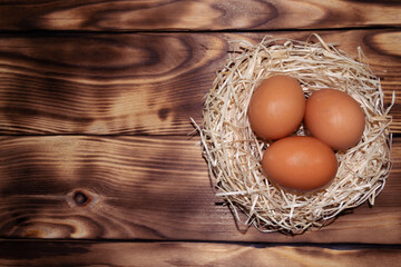 Easter brown eggs in the nest on a wooden background