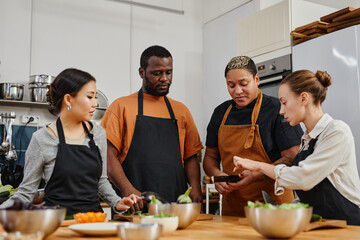 Waist up portrait of diverse group of people listening to chef in cooking class