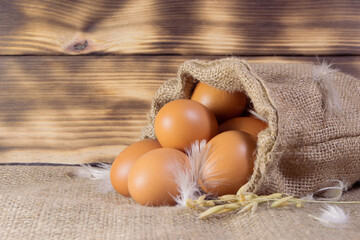 Fresh brown chicken eggs in a sacking on wooden background. Easter holidays concept
