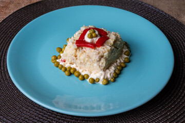 Russian salad or Olivier on a round plate, close-up.