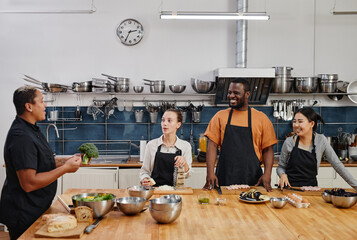 Wide angle view at female chef instructing people during cooking class in kitchen, copy space