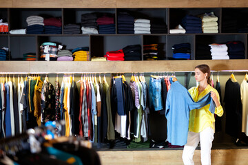 Attractive glad positive girl buying mens wear in apparel showroom