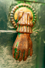 Kołatka w kształcie ręki, stara, ozdobna montowana na drzwiach.