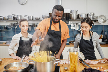 Portrait of African-American man making pasta during cooking class in kitchen interior