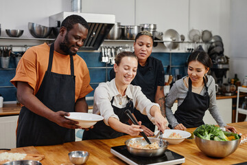 Diverse group of people cooking together during workshop in professional kitchen, copy space
