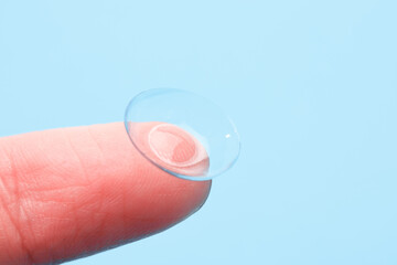 contact lenses on the finger on blue background  - Image