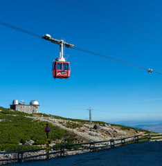 A red cable car on its way from Skalnate pleso to Lomnicky peak. Red gondola moving up to Lomnica peak in High Tatras Mountains. Slovakia.