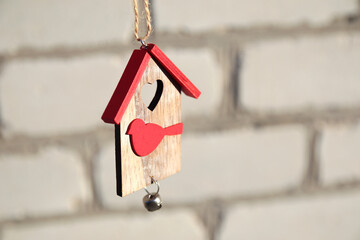 Property concept. Wooden Christmas toy house with red roof and bird on white brick wall. Christmas decoration concept. Small house. Stay home. Mock-up for design
