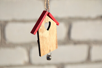Buying house concept. Wooden Christmas toy house with red roof on white brick wall. Christmas decoration concept. Small house. Stay home. Mock-up for design