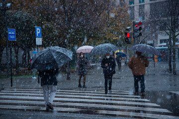 Valladolid, Spain - 23 November 2021: Peoples crossing road during snow heavy falling in city,...