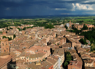 Naklejka premium View From The Tower Torre Del Mangia To The Old Town Of Siena Tuscany Italy On A Beautiful Spring Day With Dark Thunderstorm Clouds In The Sky