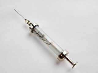 Old glass metal reusable medical syringe close-up. Retro medical instrument.
