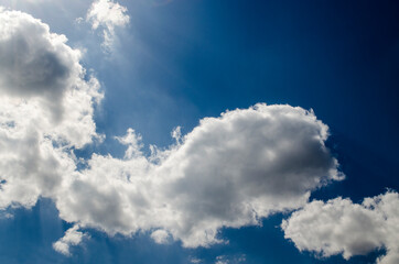 Naklejka na ściany i meble Blue sky with white clouds in sun rays. White fluffy cloud over summer sky background