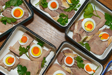 Ingredients for jellied tongue are arranging in rectangular salad dishes.