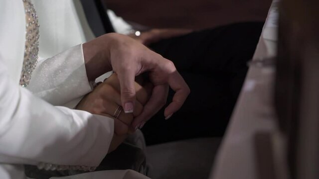 Bride and groom holding hands at wedding close up. Man and woman in love. Marriage indoors.