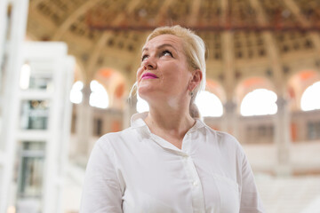 Closeup on attentive elegant senior woman wearing white blouse visiting museum