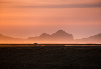 Car driving at sunset in Icelandic Ring road with Westman Islands in the background