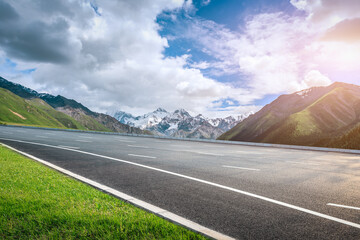 Asphalt road and snow mountain under blue sky. Highway and mountain background. © ABCDstock