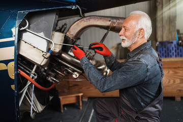 Professional senior helicopter mechanic working in air vehicle repair service.